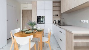 Una cocina moderna con armarios blancos, una mesa de comedor de madera y un horno empotrado.
