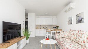 Une cuisine moderne avec des meubles blancs, un plan de travail en bois et un coin repas comprenant une table et des chaises blanches.