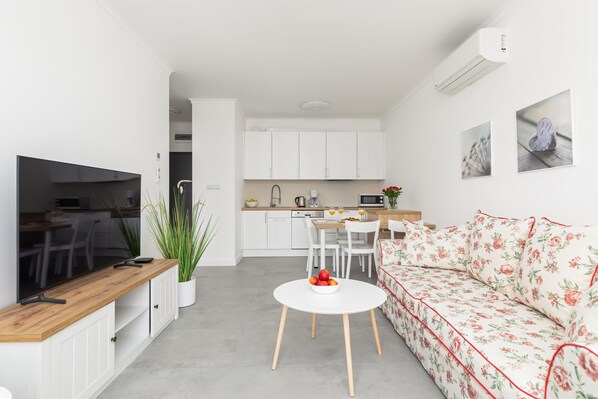 Una cocina moderna con armarios blancos, encimera de madera y comedor con mesa y sillas blancas.