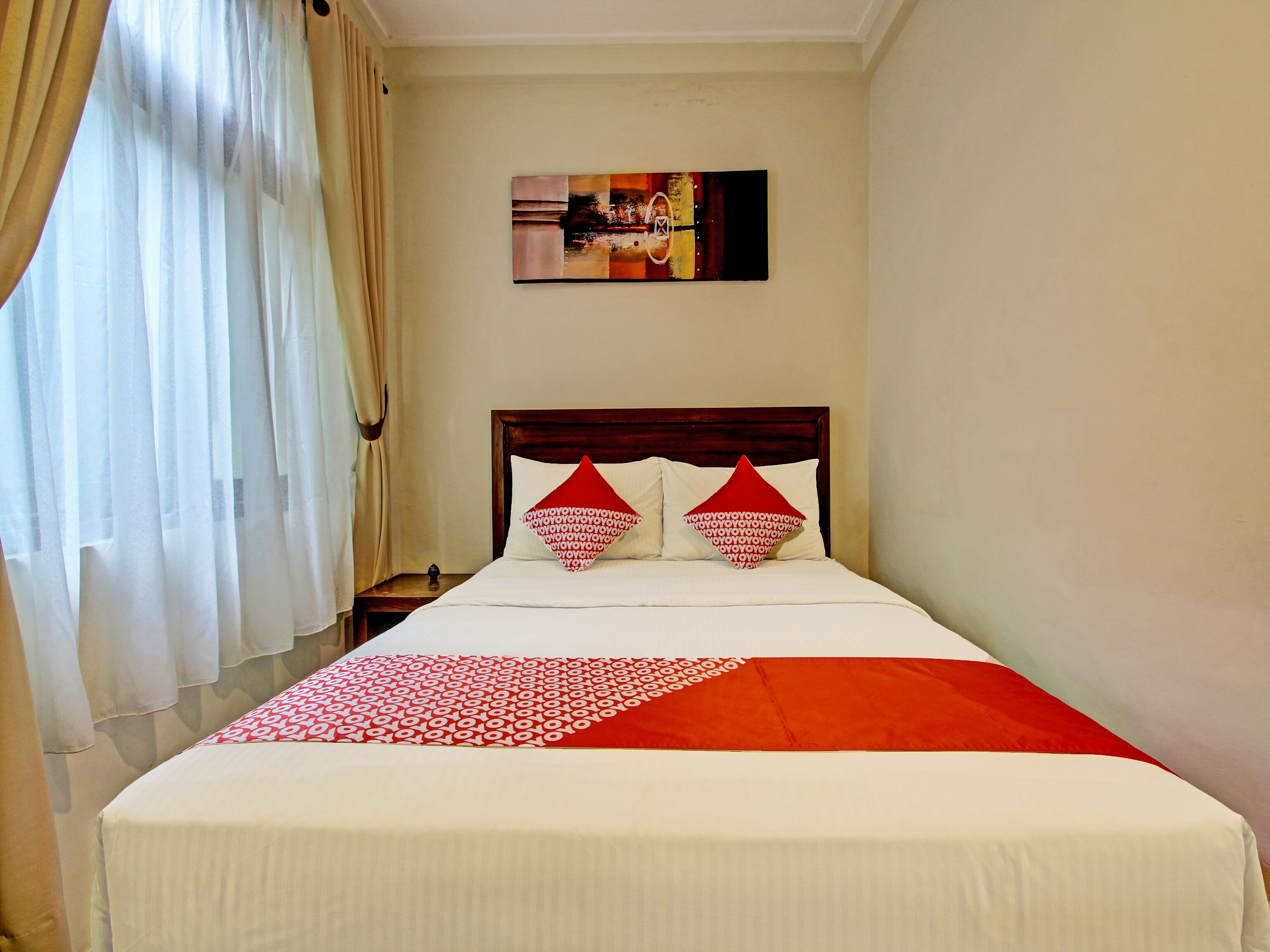 A hotel room with a bed, curtains, a painting on the wall, and a nightstand.