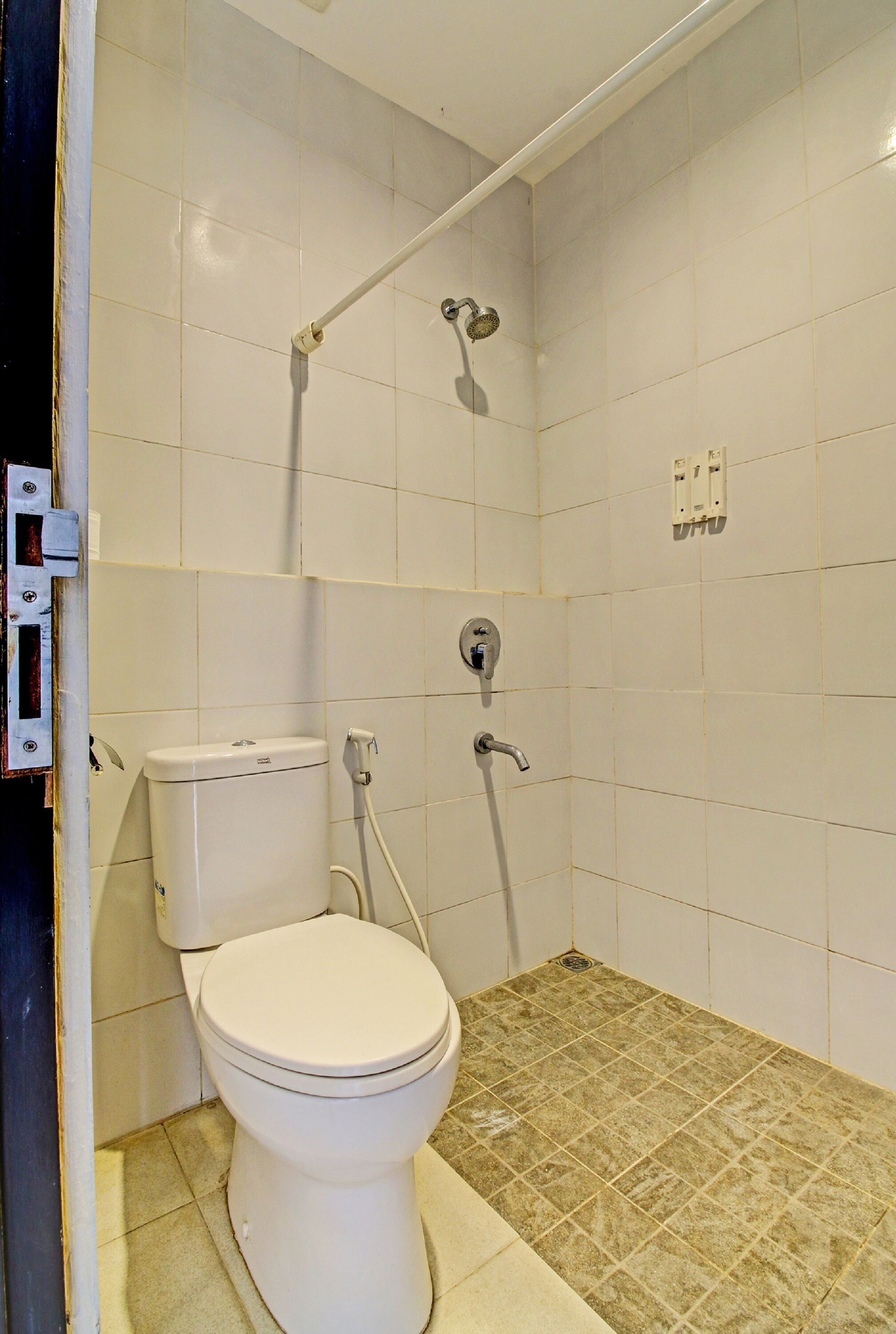 A bathroom with a toilet, a shower, and a tiled floor.