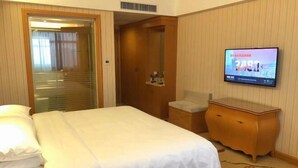 A hotel room with a bed, a television, a wooden dresser, and a door leading to a hallway. - Vienna Hotel (Jingzhou Jianli Jiangcheng) (Jianli)