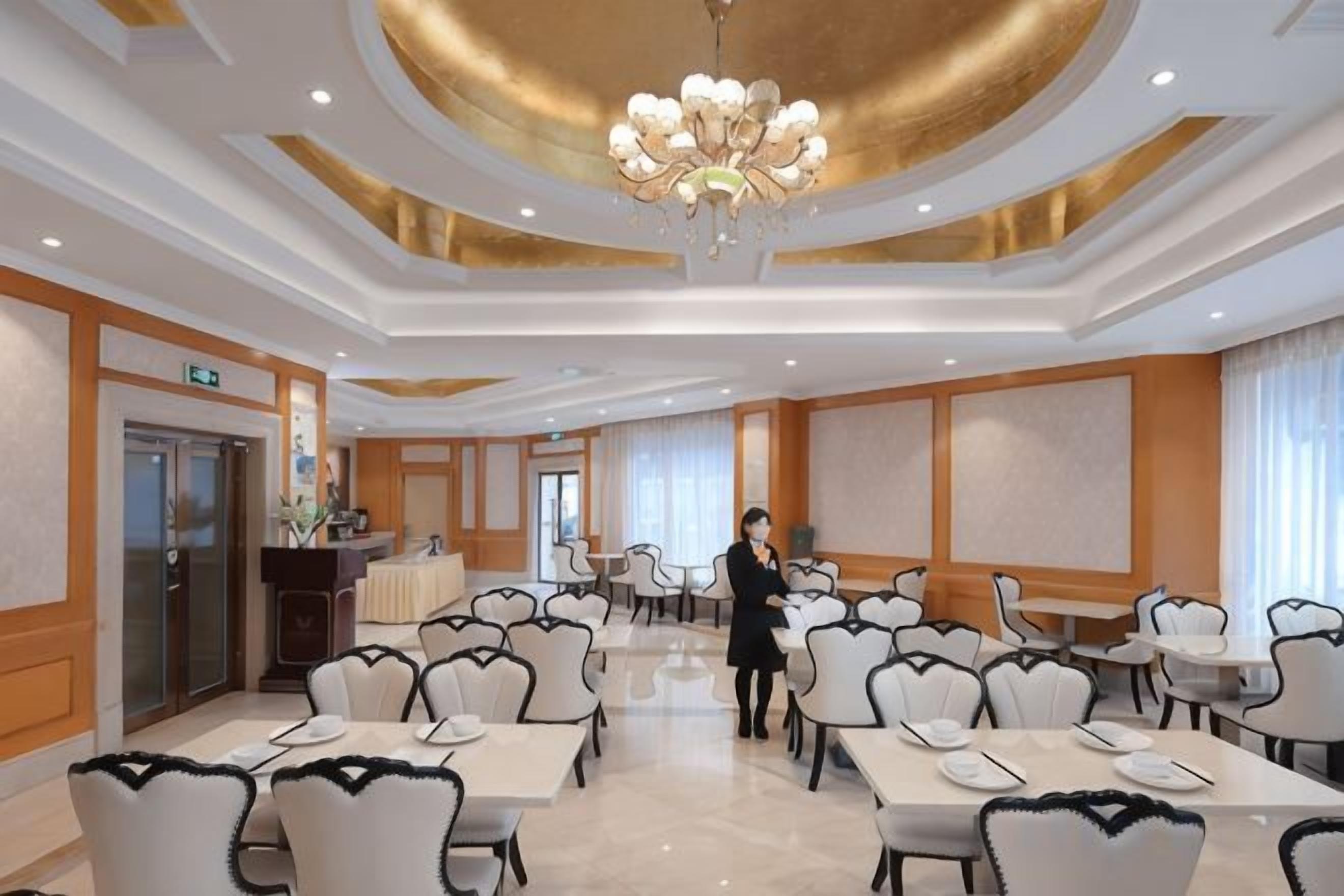 Un salón de conferencias de hotel con mesas, sillas, una araña y una recepción.