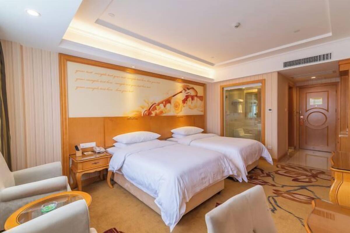 A hotel room with a large bed, two bedside tables, a desk, and a chair.