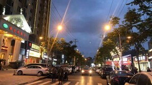 A street view at dusk with buildings, cars, and pedestrians. - Vienna Hotel (Jingzhou Jianli Jiangcheng) (Jianli)