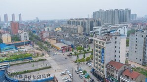 A cityscape with various buildings, including a large hotel with a sign. - Vienna Hotel (Jingzhou Jianli Jiangcheng) (Jianli)