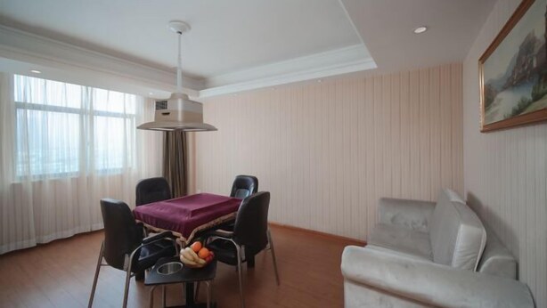 A hotel room with a dining table, four chairs, a sofa, and a painting on the wall. - Vienna Hotel (Jingzhou Jianli Jiangcheng) (Jianli)