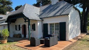 A house with a patio area featuring wicker furniture and a wooden deck.