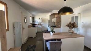A modern kitchen with a central island, a dining area with a chair, and a pendant light.