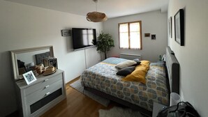 A bedroom with a bed, dresser, TV, and a window.
