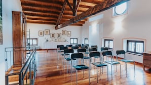 Una habitación amplia con pisos de madera y un techo alto, que presenta una hilera larga de sillas y un pequeño altar al frente.