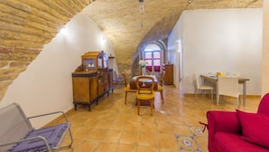 Un loft spacieux avec un plafond haut et incliné, un coin repas avec des meubles en bois et un canapé rouge.