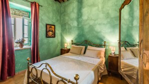 Un dormitorio con cama, mesitas de noche, un espejo y una ventana con cortinas.