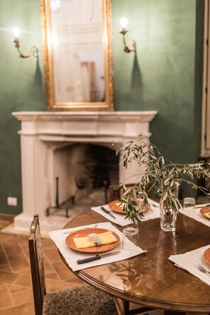 A dining table set with plates, cutlery, and a vase with greenery.