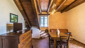 A dining area with a wooden table and chairs, a wooden dresser, and a window with curtains. - LA MASSERIA - La Colombaia - 6 (Vasto)