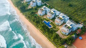 Un hotel frente a la playa con varias edificaciones, una piscina y vistas al mar.