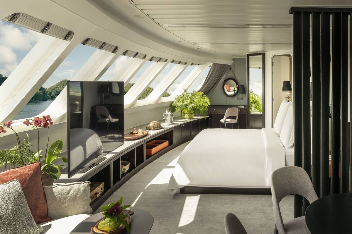 A modern interior with a bed, seating area, and a view of the outdoors.