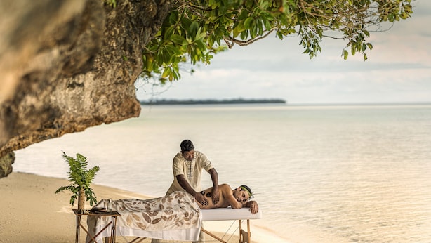 A massage table set up on a beach with a person receiving a massage. - Four Seasons Explorer, Palau - Cruising Resort (Koror)
