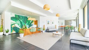 A modern hotel lobby with a reception desk, seating area, and dining space. - Studios by Aqua Natura Hotels (Porto Moniz)