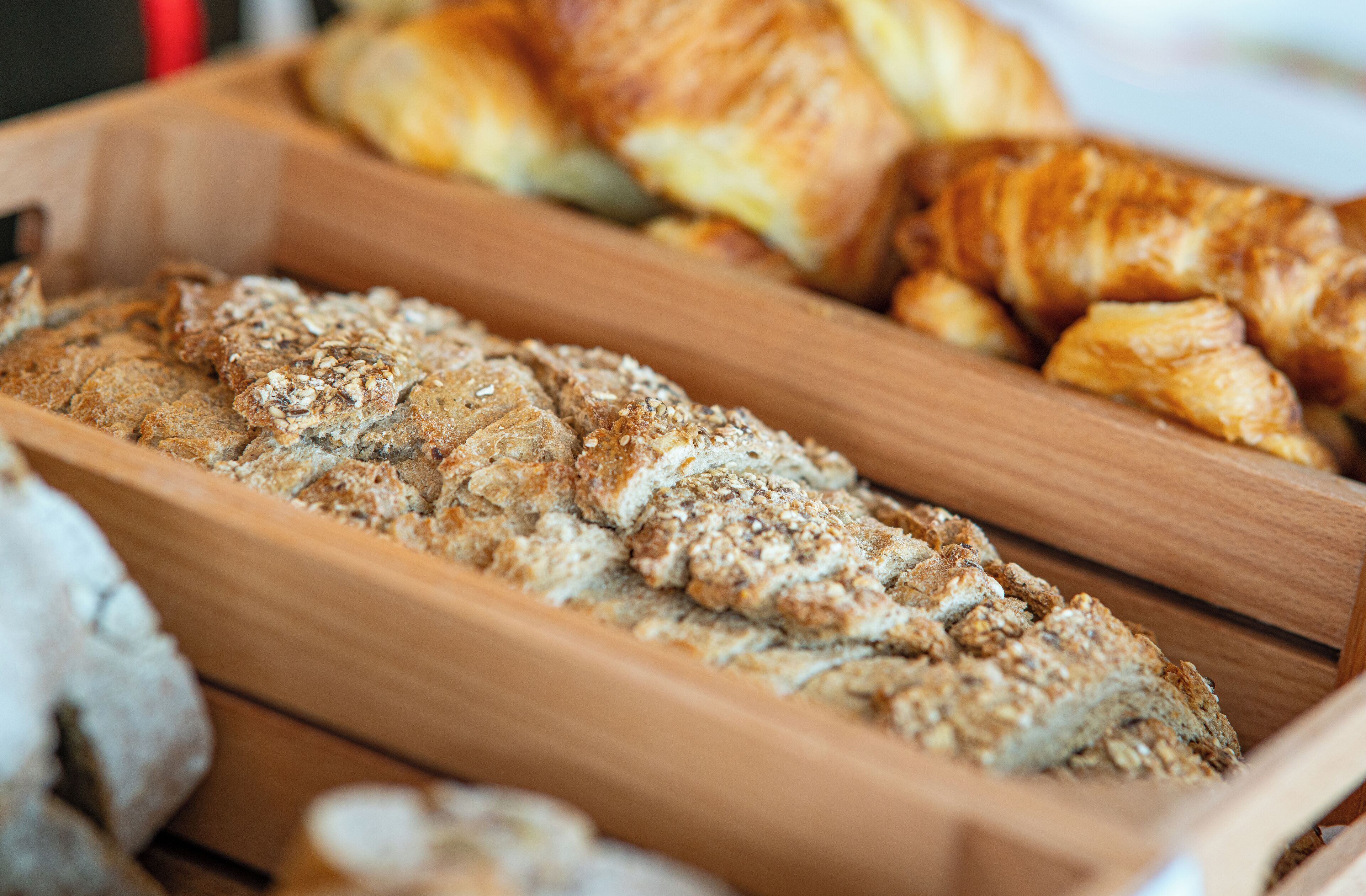 A wooden tray with various baked goods, including bread and pastries.