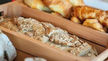 A wooden tray with various baked goods, including bread and pastries.