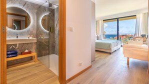 A modern hotel room with a marble bathroom, a balcony with a bed, and a view of the sea. - Studios by Aqua Natura Hotels (Porto Moniz)