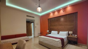 A hotel room with a large bed, a bench, a desk, and a wooden headboard. - Al Baiara Resort (Jericho)