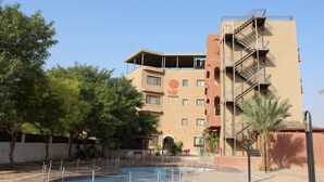 A hotel with a pool area, outdoor seating, and a palm tree. - Al Baiara Resort (Jericho)