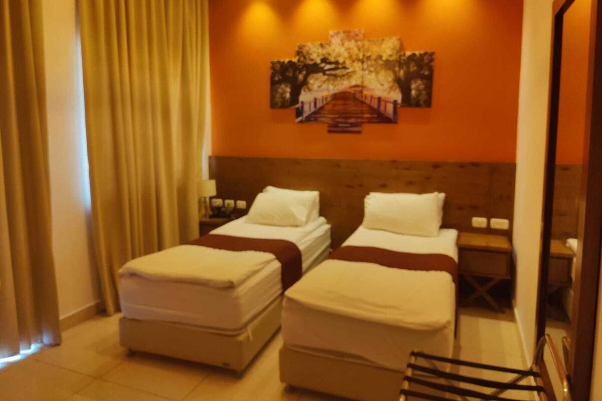 Ein Hotelzimmer mit zwei Betten, einem großen Gemälde an der Wand und einem Holzkopfteil.