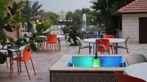 An outdoor patio area with a pool, seating arrangements, and a fountain. - Al Baiara Resort (Jericho)