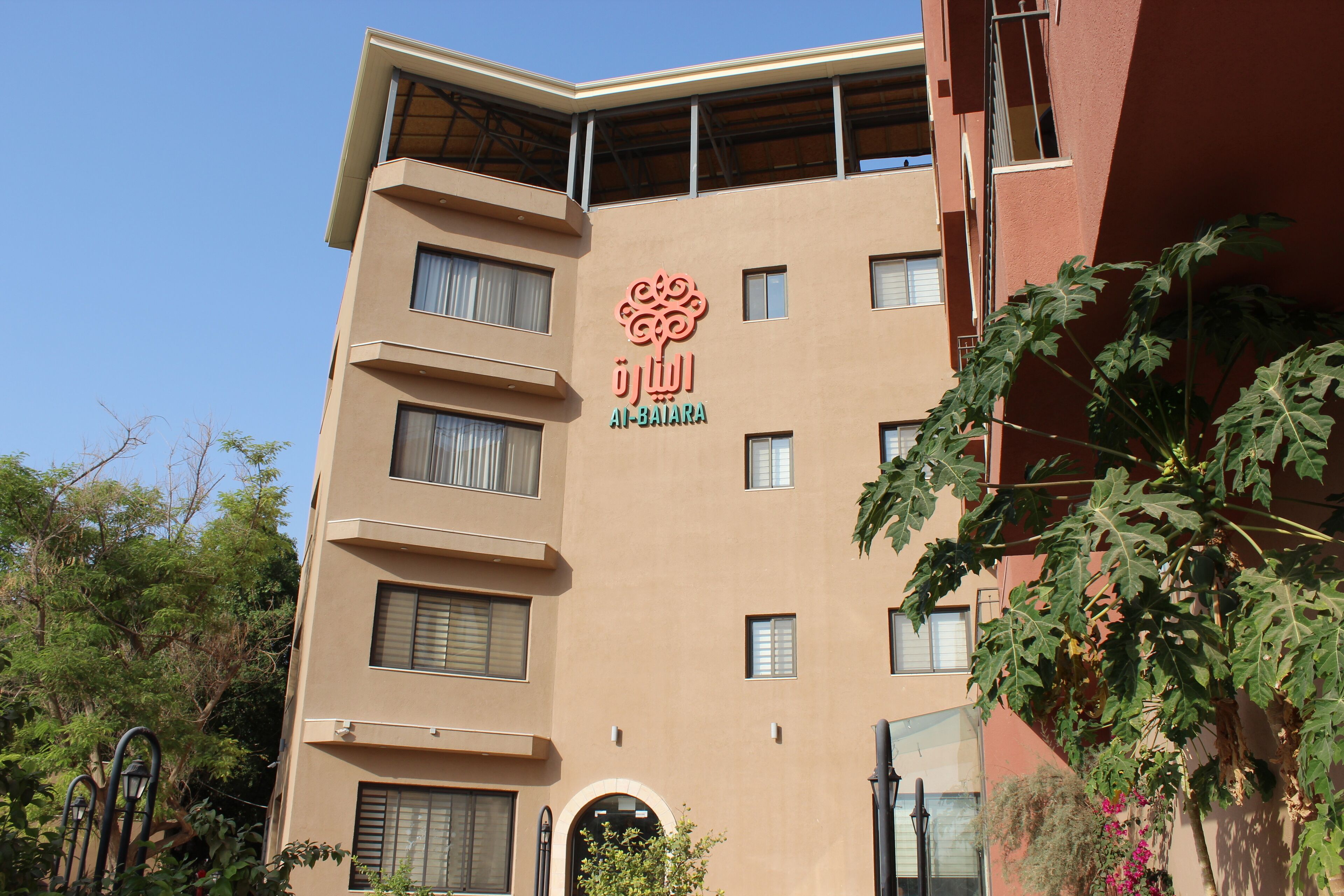 A multi-story building with a beige facade, a prominent logo, and a balcony.