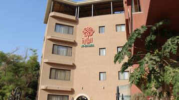 A multi-story building with a beige facade, a prominent logo, and a balcony.