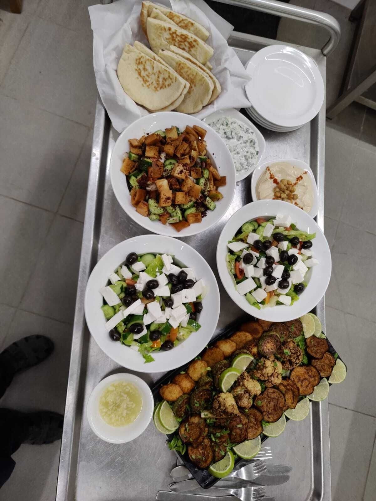 Un plateau contenant divers plats, notamment des galettes, des salades et des légumes rôtis.