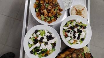 Un plateau contenant divers plats, notamment des galettes, des salades et des légumes rôtis.