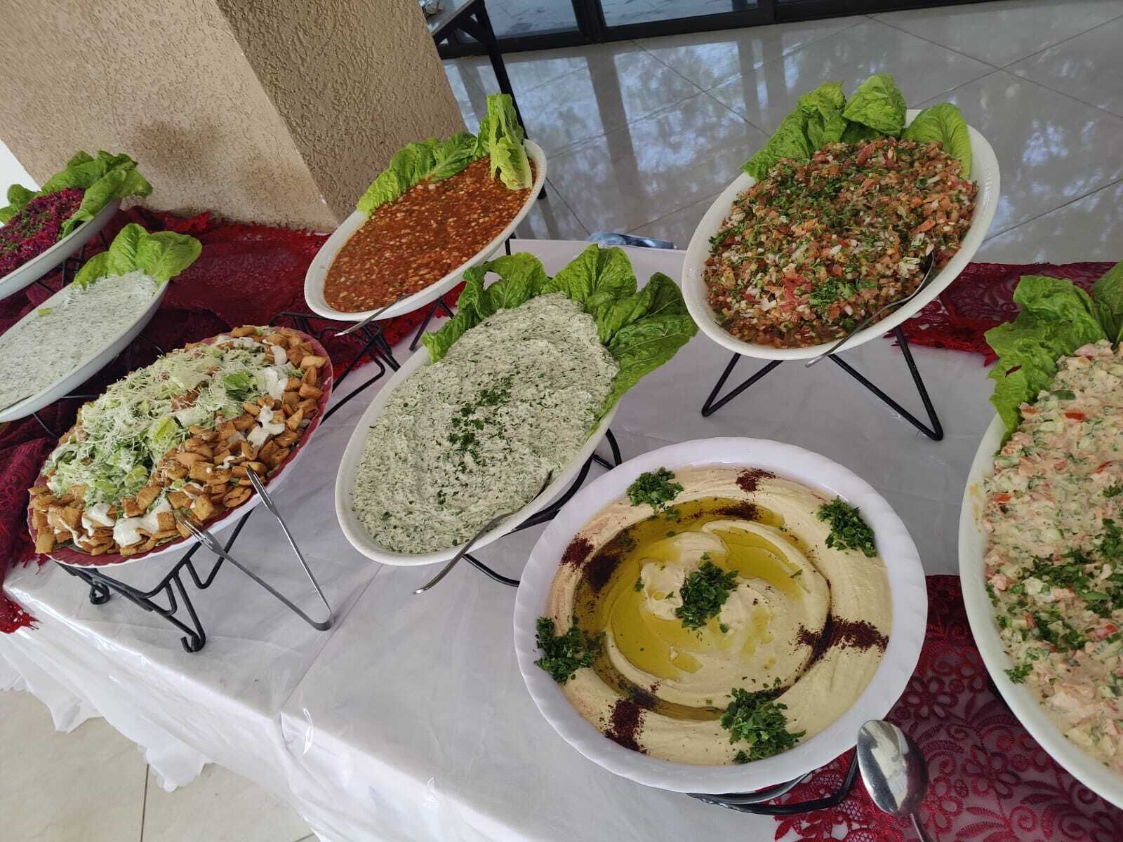 Una mesa con diversos platos, incluyendo hummus, arroz y ensaladas, sobre un mantel.