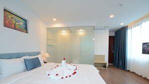A hotel room with a neatly made bed, a glass partition, a wooden floor, and a painting on the wall. - Hanoi Prime Center Hotel & Spa (Hanoi)