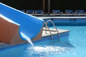 A swimming pool with a blue slide, metal ladder, and blue lounge chairs. - Sa Gavina C building, 2 Bedroom apartment, WIFI, POOL, LIFT, balcony or terace. (Estartit)