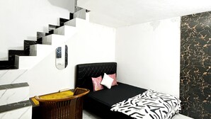 A compact bedroom with a bed, a small wooden chair, a wicker basket, and a staircase. - Kost Harian Semarang Murah (Semarang)