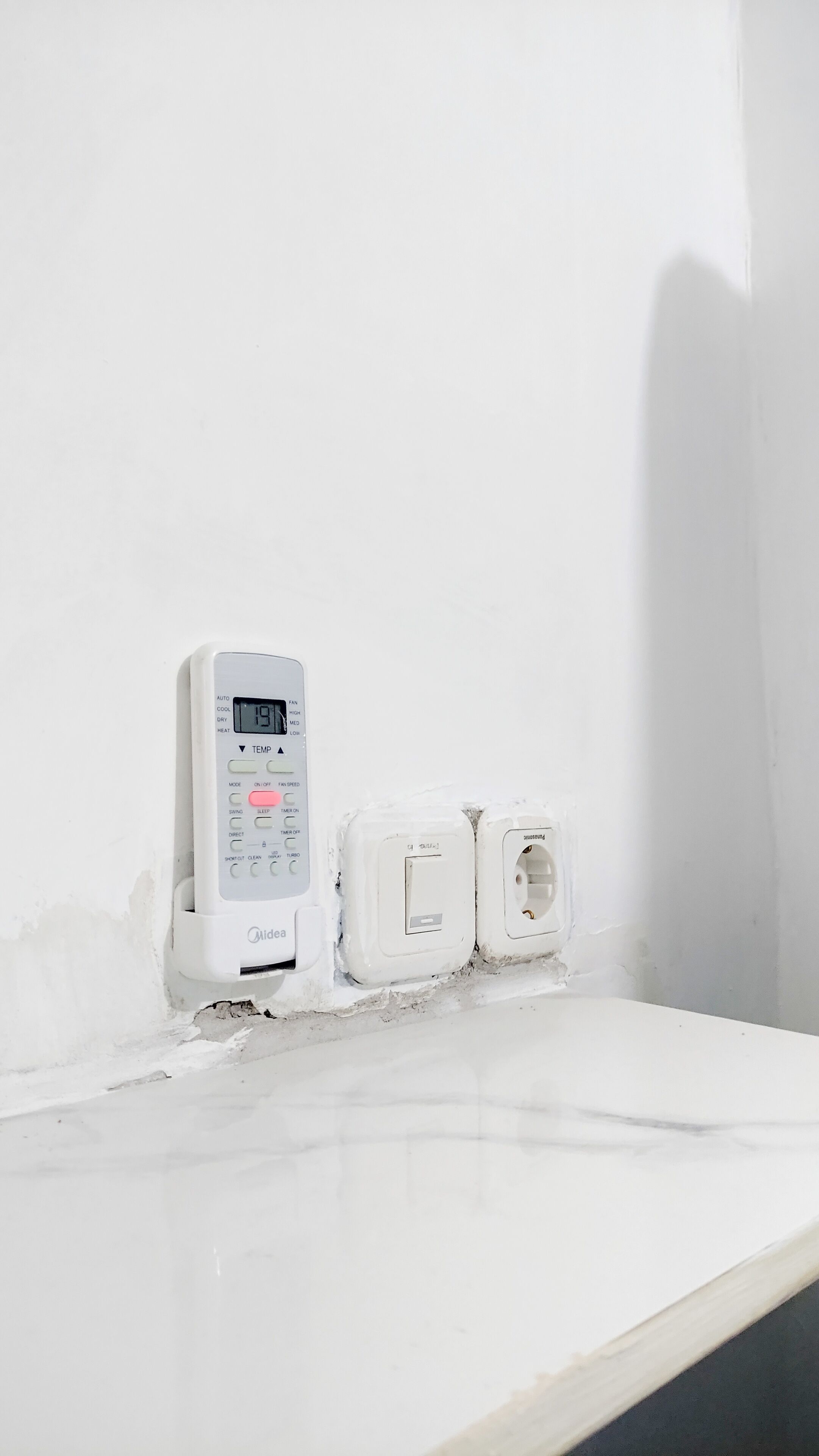 A thermostat and electrical outlets on a white wall.