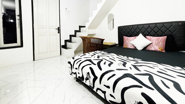 A bedroom with a zebra-patterned bed, a black headboard, and a staircase with white and black marble steps. - Kost Harian Semarang Murah (Semarang)