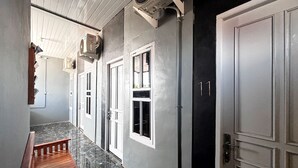 A corridor with a wooden bench, white doors, and a black door with the number 11. - Kost Harian Semarang Murah (Semarang)