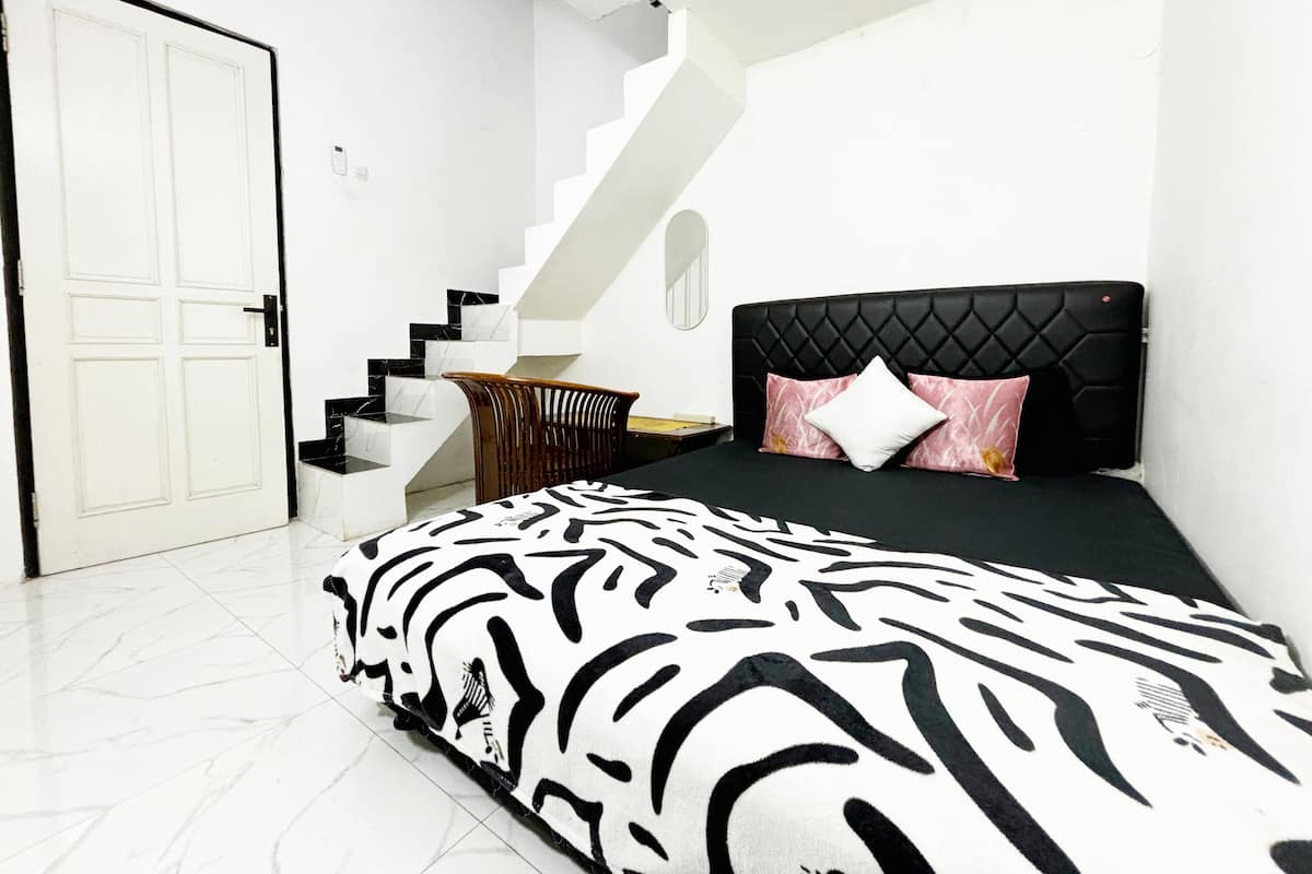 A bedroom with a bed, a staircase, and a door.