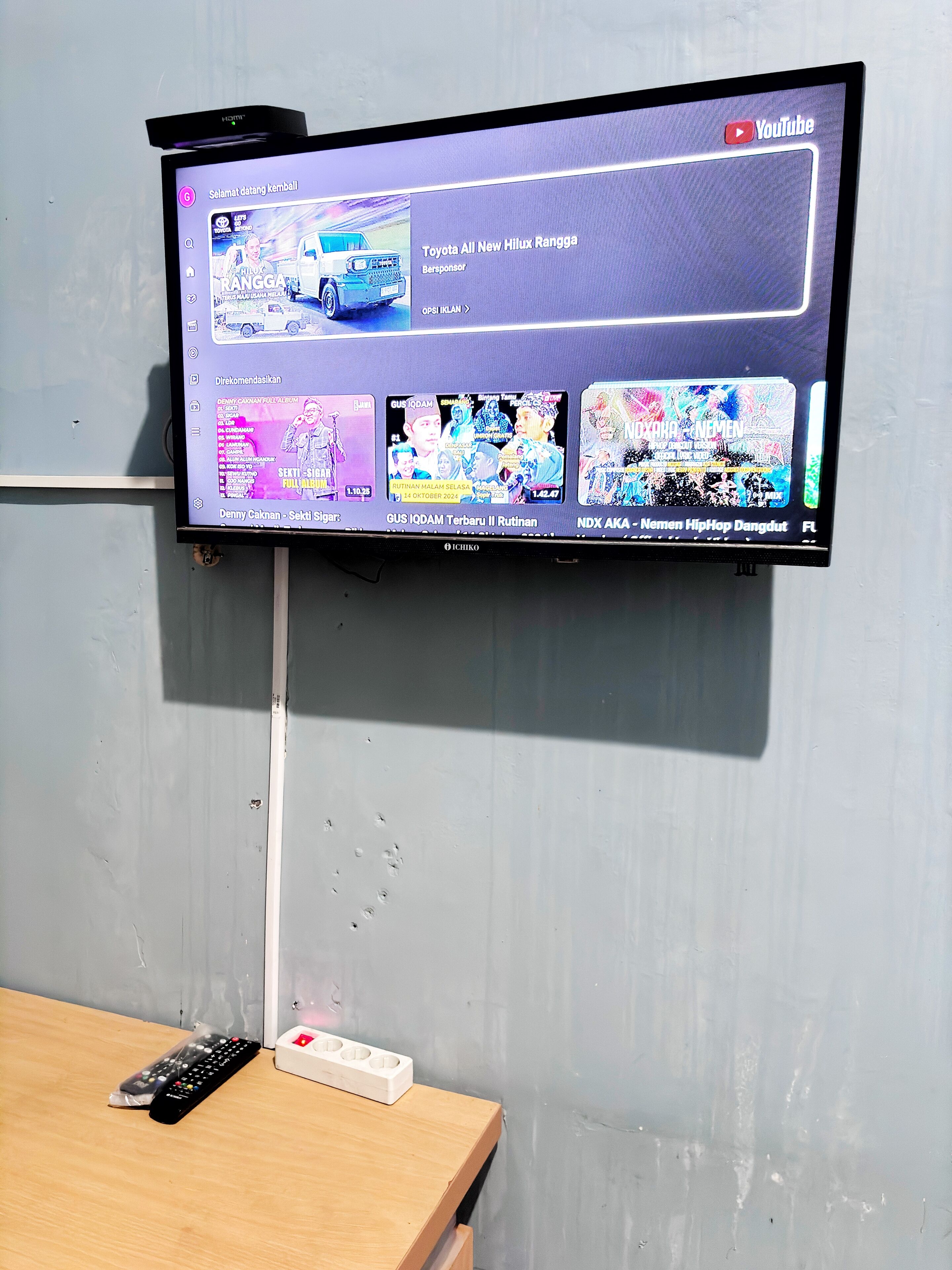 A flat-screen TV mounted on a wall displaying various video thumbnails.