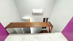 A narrow stairwell with a wooden handrail, a white wall, and a white ceiling. - Kost Harian Semarang Murah (Semarang)
