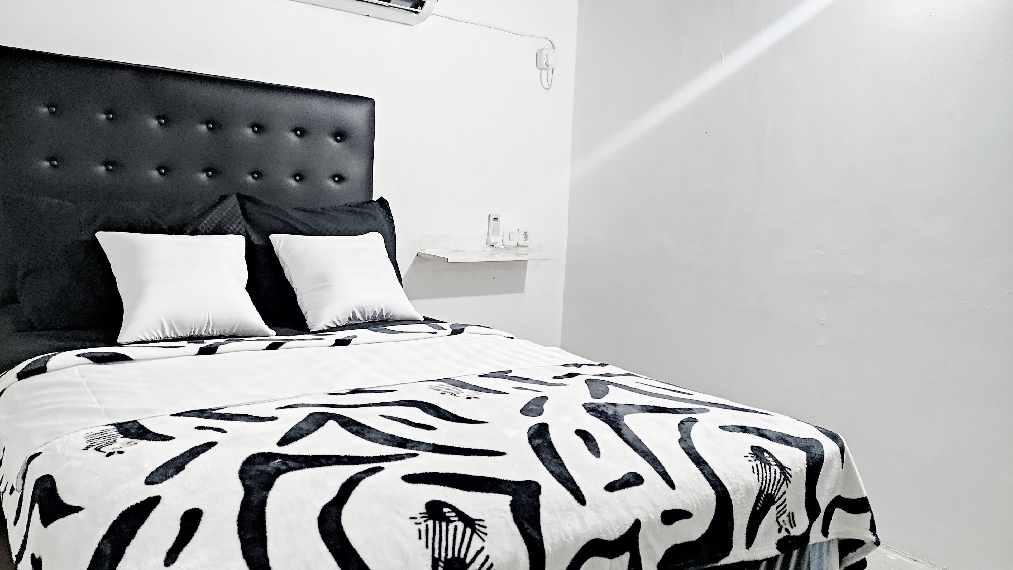 A bed with a tufted headboard, two white pillows, and a patterned bedspread.