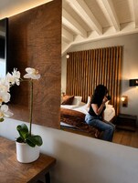 Un dormitorio moderno con una pared de acento de madera, una cama con cabecera marrón y una orquídea en maceta sobre una mesa de madera.