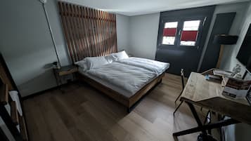 Un dormitorio con cama de madera, un escritorio y una silla.