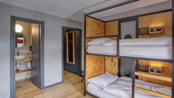 Une chambre avec un lit superposé, une tête de lit en bois, une table de chevet et un miroir.