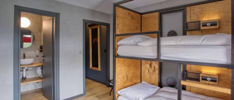 Une chambre avec un lit superposé, une tête de lit en bois, une table de chevet et un miroir.
