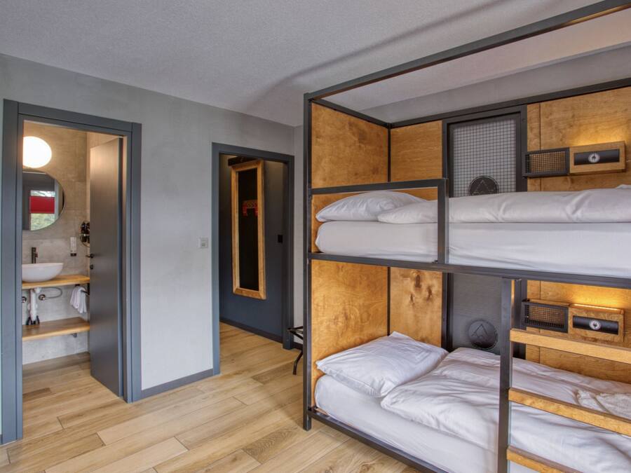 Une chambre avec un lit superposé, une tête de lit en bois, une table de chevet et un miroir.
